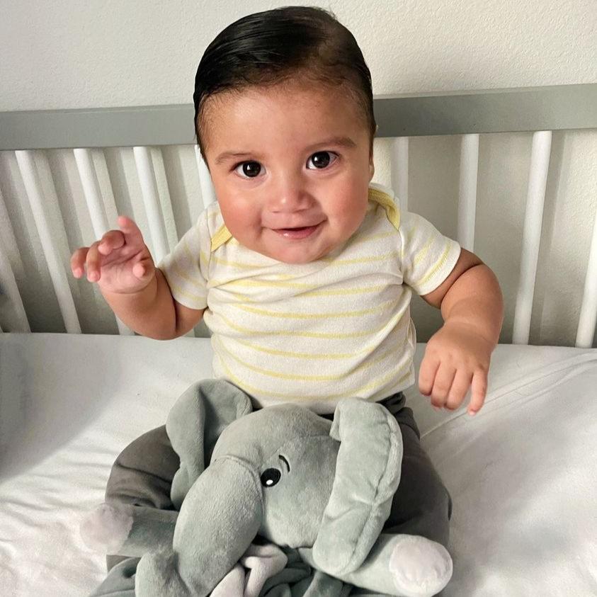 image of young toddler so happy with his Love By Emi white noise and lullaby plushie Ellie the Elephant 